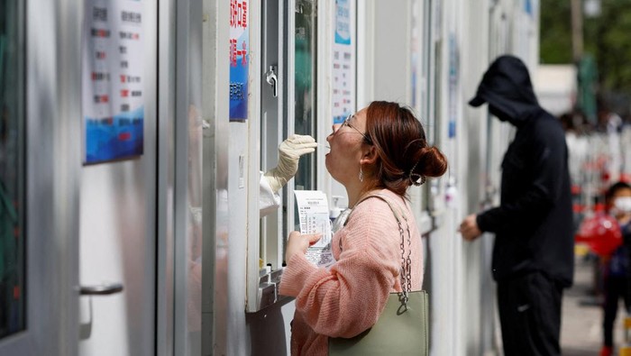 People line up outside a makeshift nucleic acid testing site during a mass testing for the coronavirus disease (COVID-19) in Haidian district of Beijing, China April 26, 2022. REUTERS/Carlos Garcia Rawlins