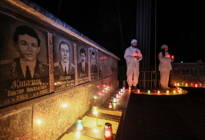 A staff of the Chornobyl nuclear plant holds a candle as he visits a memorial dedicated to firefighters and workers who died after the Chornobyl nuclear disaster, during a night service, amid Russias invasion of Ukraine, in Slavutych, Ukraine April 26, 2022.  REUTERS/Gleb Garanich