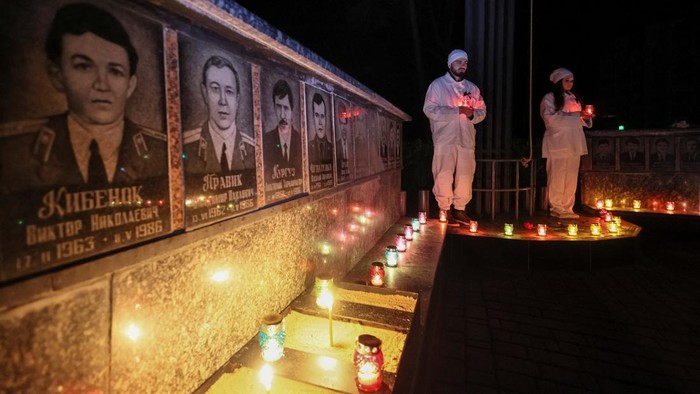 A staff of the Chornobyl nuclear plant holds a candle as he visits a memorial dedicated to firefighters and workers who died after the Chornobyl nuclear disaster, during a night service, amid Russia's invasion of Ukraine, in Slavutych, Ukraine April 26, 2022.  REUTERS/Gleb Garanich
