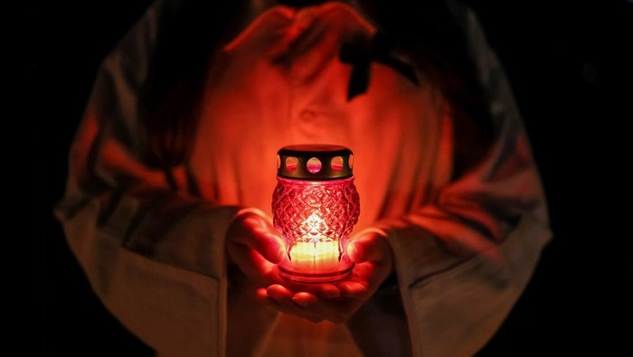 A staff of the Chornobyl nuclear plant holds a candle as he visits a memorial dedicated to firefighters and workers who died after the Chornobyl nuclear disaster, during a night service, amid Russias invasion of Ukraine, in Slavutych, Ukraine April 26, 2022.  REUTERS/Gleb Garanich