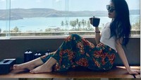 Sluuurrp! Vira yang juga hobi traveling ini asyik meneguk segelas teh hangat sambil menikmati pemandangan. Langit cerah, lautan dan pegunungan menjadi view di depan Vira. Foto: instagram @virramelia
