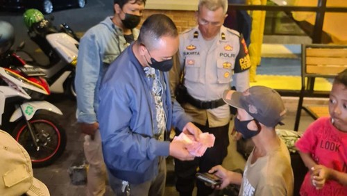Polisi saat memeriksa dompet Hariyanto, gepeng tajir yang kedapatan membawa uang jutaan di Denpasar