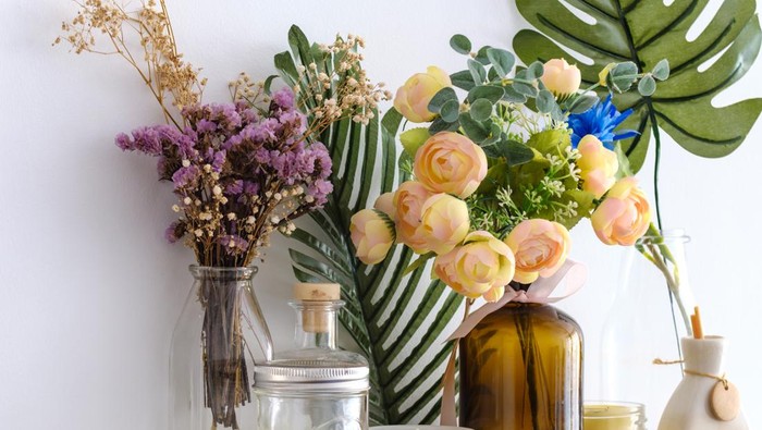 Fake flowers in vases on white wall
