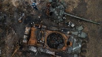 Dalam foto udara ini terlihat seorang pria tengah memotret foto tank militer Rusia yang hancur di kawasan Dmytrivka, Ukraina, Kamis (27/4/2022). (Alexey Furman/Getty Images).