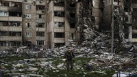 Seorang prajurit Ukraina berjalan di tengah puing-puing bangunan yang rusak berat oleh beberapa pemboman Rusia di dekat garis depan di Kharkiv, Ukraina, Senin, 25 April 2022. (AP Photo/Felipe Dana)