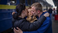 Oleksandr, 26, mencium calon istrinya, Egor, 2, dan istrinya Alyona, 26, saat mereka bertemu di stasiun kereta api setelah lebih dari dua bulan berpisah karena perang di Kyiv, Ukraina pada Sabtu, 23 April 2022. (AP Photo/Emilio Morenatti)