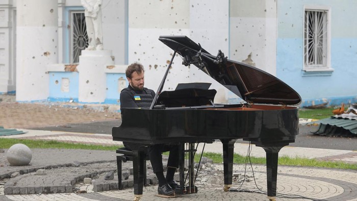 Lithuanian musician Darius Mazintas plays a piano in front of the Central House of Culture destroyed during Russia's invasion, in the town of Irpin, outside Kyiv, Ukraine April 26, 2022.  REUTERS/Mykola Tymchenko