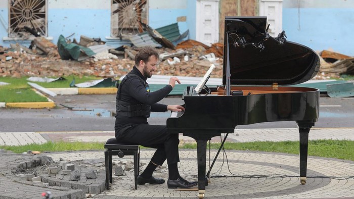 Lithuanian musician Darius Mazintas plays a piano in front of the Central House of Culture destroyed during Russia's invasion, in the town of Irpin, outside Kyiv, Ukraine April 26, 2022.  REUTERS/Mykola Tymchenko