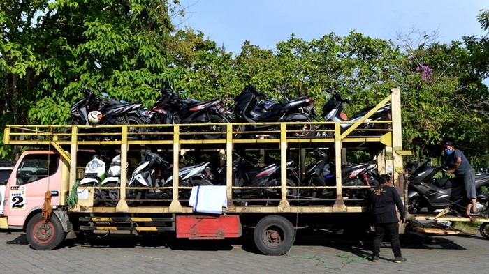 Pekerja mengangkut sepeda motor pemudik ke atas truk di kawasan Renon, Denpasar, Bali, Kamis (28/4/2022). Pengangkutan sepeda motor pemudik menuju sejumlah daerah di Banyuwangi, Jawa Timur secara gratis tersebut dilakukan sebagai salah satu upaya untuk mengurangi angka kecelakaan pemudik bersepeda motor. ANTARA FOTO/Fikri Yusuf/nym.