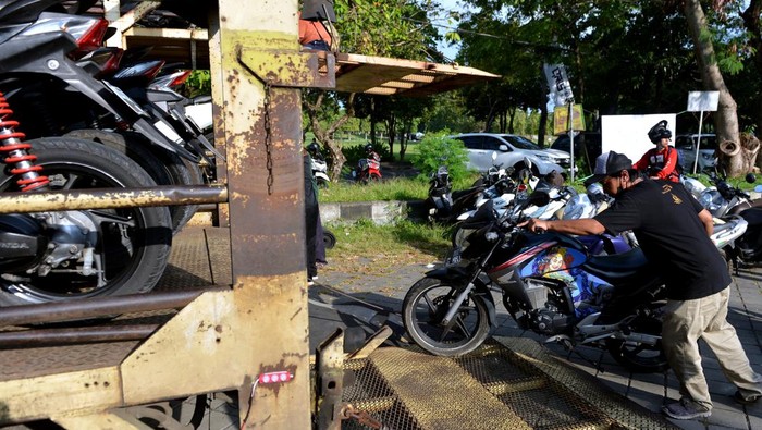 Pekerja mengangkut sepeda motor pemudik ke atas truk di kawasan Renon, Denpasar, Bali, Kamis (28/4/2022). Pengangkutan sepeda motor pemudik menuju sejumlah daerah di Banyuwangi, Jawa Timur secara gratis tersebut dilakukan sebagai salah satu upaya untuk mengurangi angka kecelakaan pemudik bersepeda motor. ANTARA FOTO/Fikri Yusuf/nym.