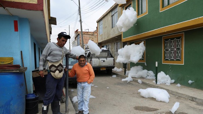 Men talk in a street where there is polluting foam generated by a river full of waste, in Mosquera, Colombia April 27, 2022. REUTERS/Luisa Gonzalez