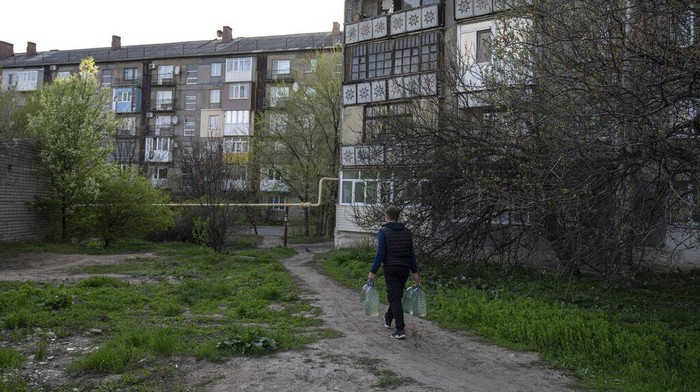 Local residents receive drinking water at a distribution centre in Toretsk, eastern Ukraine, Monday, April 25, 2022. Toretsk residents have had no access to water for more than two months because of the war. (AP Photo/Evgeniy Maloletka)