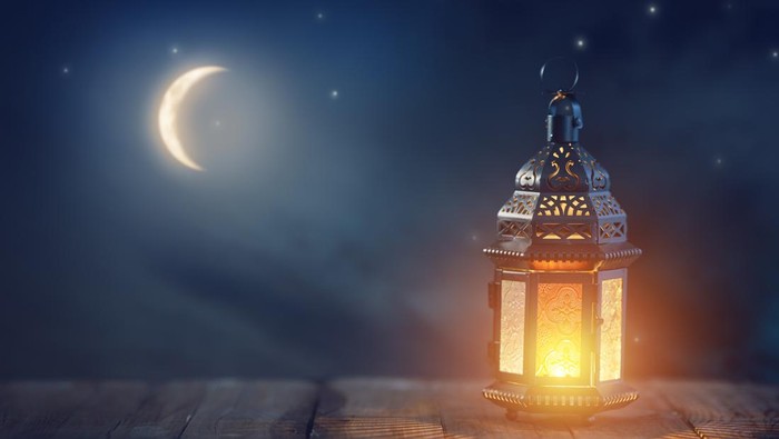 Ornamental Arabic lantern with burning candle glowing at night. Festive greeting card, invitation for Muslim holy month Ramadan Kareem.