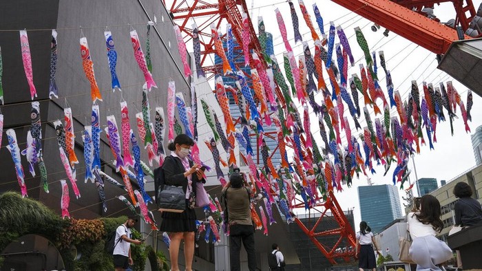 Japan Daily Life People take pictures of Koinobori, colorful carp streamers, on display at the base of Tokyo Tower Wednesday, April 27, 2022, in Tokyo. Koinobori are traditionally flown to celebrate Children's Day on May 5. (AP Photo/Kiichiro Sato)