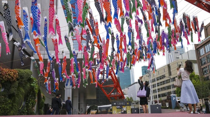 People take pictures of Koinobori, colorful carp streamers, on display at the base of Tokyo Tower Wednesday, April 27, 2022, in Tokyo. Koinobori are traditionally flown to celebrate Children's Day on May 5. (AP Photo/Kiichiro Sato)