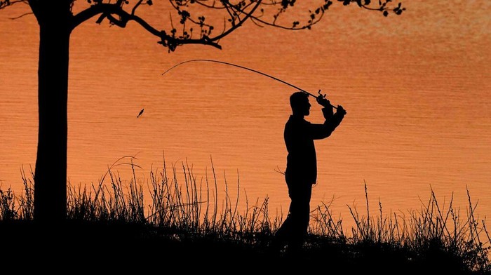 Kansas Daily Life A man fishes at sunset, Tuesday, April 26, 2022, at Shawnee Mission Lake in Shawnee, Kan. (AP Photo/Charlie Riedel)
