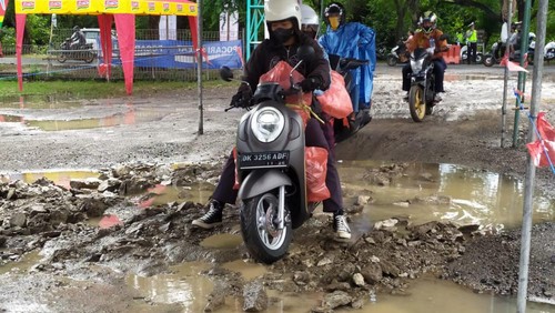 Pemudik nampak berhati-hati melintasi landasan parkir di Pos Pemeriksaan Gilimanuk yang becek usai diguyur hujan.
