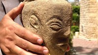 Kepala patung ini berukuran sekitar 22 cm yang menunjukan wajah demi dengan mahkota ular di atasnya. Patung ini pun diukir di batu kapur. (dok BBC)