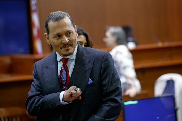 Actor Johnny Depp watches a pre-recorded deposition testimony of Christian Carino at the Fairfax County Circuit Court in Fairfax, Va., Wednesday, April 27, 2022. Depp sued his ex-wife actress Amber Heard for libel in Fairfax County Circuit Court after she wrote an op-ed piece in The Washington Post in 2018 referring to herself as a 