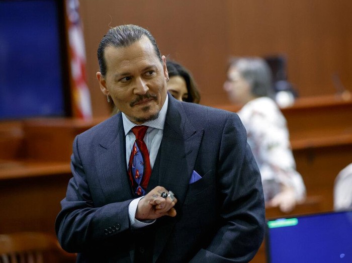 Actor Johnny Depp watches a pre-recorded deposition testimony of Christian Carino at the Fairfax County Circuit Court in Fairfax, Va., Wednesday, April 27, 2022. Depp sued his ex-wife actress Amber Heard for libel in Fairfax County Circuit Court after she wrote an op-ed piece in The Washington Post in 2018 referring to herself as a public figure representing domestic abuse. (Jonathan Ernst/Pool Photo via AP)