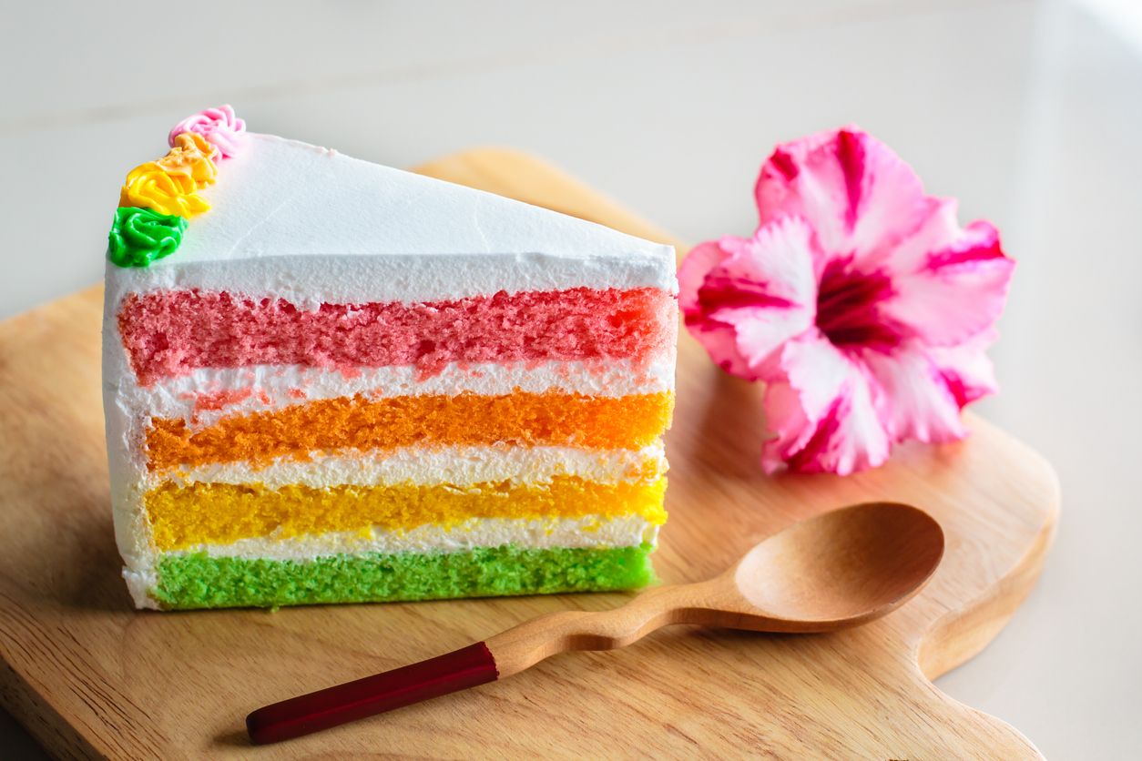 Slice of rainbow cake, Delicious rainbow cake on wood plate.