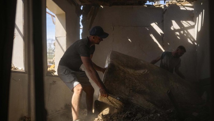 Roket Rusia Hantam Rumah di Zaporizhzhia, Lukisan Ini Buktinya Yaroslav Lazarenko, left, and his cousin Alexei remove debris from his destroyed house after a Russian rocket, hit by Ukraine's anti-aircraft system, stroke in a residencial area in Zaporizhzhia, Ukraine, Thursday, April 28, 2022. The strike came as parts of southern Ukraine prepare for a further advance by Russian forces who seek to strip the country of its seacoast. (AP Photo/Francisco Seco)
