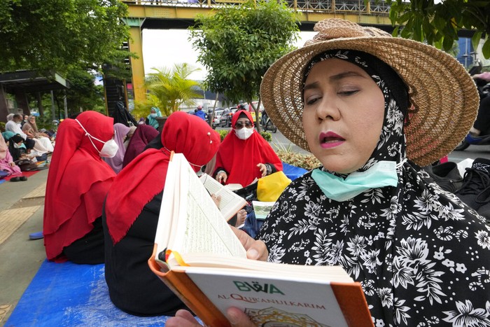 Trotoar di Bekasi yang Jadi Tempat Tadarus Al-Qur'an A pedestrian walks as muslim reads the Quran during the last week of Ramadan at pedestrian street in Bekasi, West Java, Indonesia, Wednesday, April 27, 2022. Muslims across the world are observing the holy fasting month of Ramadan, where they refrain from eating, drinking and smoking from dawn to dusk(AP Photo/Achmad Ibrahim)
