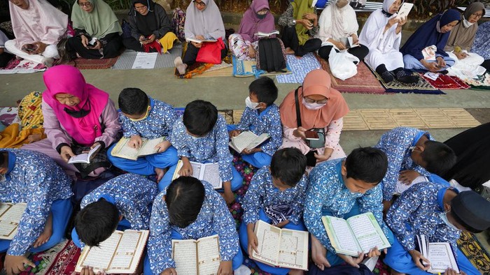 A pedestrian walks as muslim reads the Quran during the last week of Ramadan at pedestrian street in Bekasi, West Java, Indonesia, Wednesday, April 27, 2022. Muslims across the world are observing the holy fasting month of Ramadan, where they refrain from eating, drinking and smoking from dawn to dusk(AP Photo/Achmad Ibrahim)
