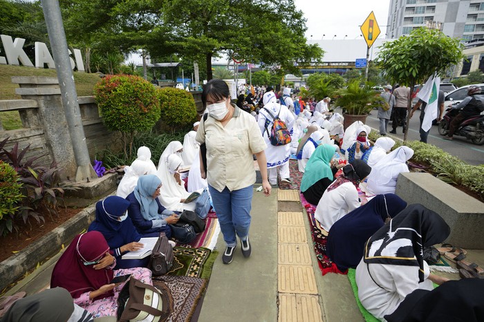 Trotoar di Bekasi yang Jadi Tempat Tadarus Al-Qur'an A pedestrian walks as muslim reads the Quran during the last week of Ramadan at pedestrian street in Bekasi, West Java, Indonesia, Wednesday, April 27, 2022. Muslims across the world are observing the holy fasting month of Ramadan, where they refrain from eating, drinking and smoking from dawn to dusk(AP Photo/Achmad Ibrahim)