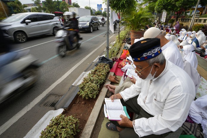 Trotoar di Bekasi yang Jadi Tempat Tadarus Al-Qur'an A pedestrian walks as muslim reads the Quran during the last week of Ramadan at pedestrian street in Bekasi, West Java, Indonesia, Wednesday, April 27, 2022. Muslims across the world are observing the holy fasting month of Ramadan, where they refrain from eating, drinking and smoking from dawn to dusk(AP Photo/Achmad Ibrahim)