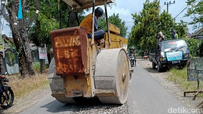 Pekerja melakukan perbaikan jalan rusak di Lamongan.