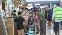 Penumpang tengah check-in dan mendata barang bagasi di counter maskapai.