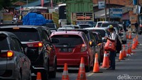 Seorang pedagang asongan menjajakan dagangannya kepada pengendara yang terjebak macet.