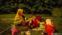 Seorang anak tengah disuapi mi instan oleh ibunya saat beristirahat di sekitar rest area Km 86.