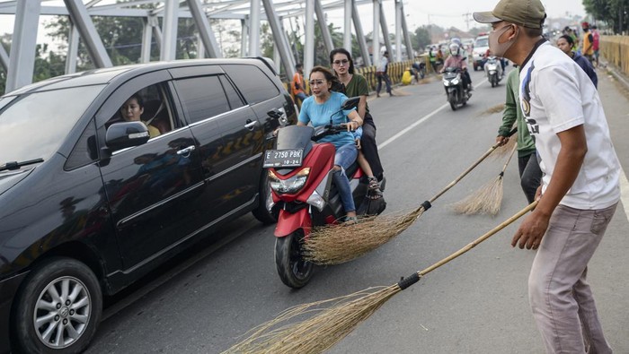 Potret Pencari Sedekah dengan Sapu di Jalanan Indramayu Warga mengambil uang dengan menggunakan sapu saat diberikan oleh pengendara yang melintas di Jembatan Sewo, Indramayu, Jawa Barat, Jumat (29/4/2022). Memasuki musim mudik Lebaran, jumlah pencari uang sedekah di kawasan itu meningkat dibanding hari biasa. ANTARA FOTO/M Risyal Hidayat/nym.