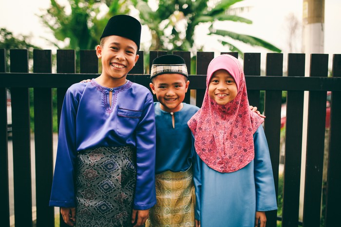 Three sibling playing in front of house during eid celebration in Malaysia