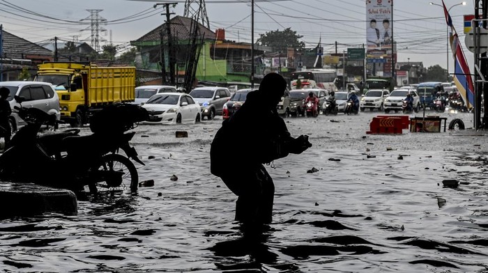 Pengendara sepeda motor melintas saat banjir di kawasan Jalan Akses Tol Cibitung, Bekasi, Jawa Barat, Sabtu (30/4/2022). Banjir di kawasan tersebut disebabkan banyaknya sampah yang menyumbat saluran air (drainase).  ANTARA FOTO/Muhammad Adimaja