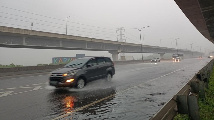 Kondisi di Tol Jakarta Cikampek hujan. Namun pemudik tetap ngebut di jalan.