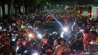 Tampak dua unit mobil terjebak di lautan pemotor.   