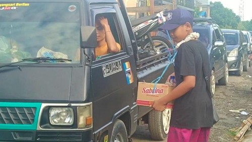 Salah satu warga Gilimanuk saat menjadi pedagang asong dadakan menawarkan dagangannya kepada para pemudik yang terjebak antrean panjang.