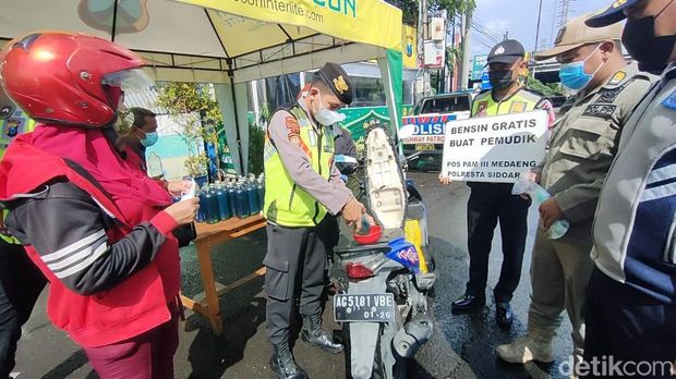 Polisi membagikan BBM pertalite dan pertamax gratis di Medaeng, Sidoarjo.