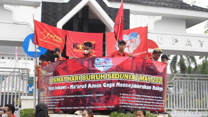 Puluhan buruh dari Federasi Serikat Pekerja Karawang (Fspek) Kongres Aliansi Serikat Buruh (Kasbi) memajangkan poster bertuliskan ‘Rezim Jokowi- Amin Gagal Sejahterakan Rakyat’ di depan gerbang Pemkab Karawang.