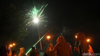 Peserta takbir keliling menonton pertunjukan kembang api saat melintas area persawahan di dusun Ngaran, Seyegan, Sleman, Yogyakarta.