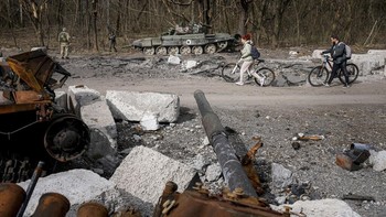 Penduduk lokal berjalan dengan latar belakang tank Rusia yang rusak di area Cherniniv, Ukraina. Cukup banyak tank Rusia yang menjadi korban rudal Ukraina ataupun serangan drone. Di media sosial, lalu lalang tank Rusia hancur atau rusak. Foto: Associated Press