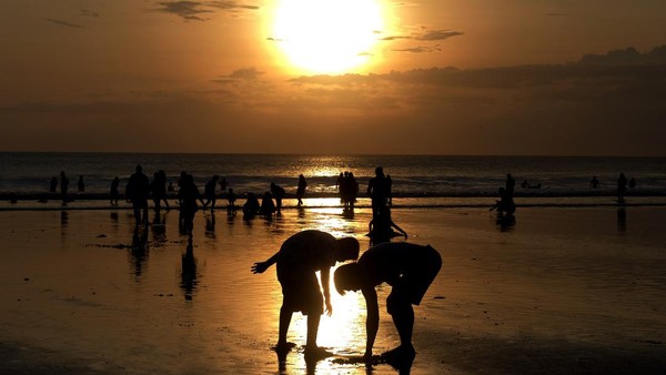 Wisatawan menikmati pemandangan matahari terbenam saat libur Lebaran di Pantai Kuta.