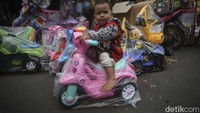 Seorang anak mencoba motor mainan yang berada di salah satu kios di Pasar Gembrong.