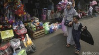 Seorang ibu dan anaknya melintas di depan kios mainan di Pasar Gembrong.