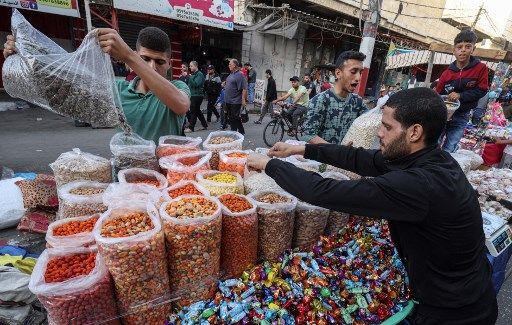 Vendors replenish their stock as Palestinians shop at a market in Rafah in the southern Gaza Strip, on May 1, 2022, on the eve of Eid al-Fitr which marks the end of the Muslim fasting month of Ramadan. (Photo by SAID KHATIB / AFP)