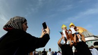 Orang-orang berdiri saat mereka berfoto selama perayaan setelah orang-orang Palestina melakukan salat Idul Fitri.