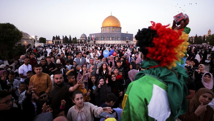 A man holds up a young girl during celebrations after Palestinians performed Eid al-Fitr prayers which marks the end of the holy fasting month of Ramadan, on the compound known to Muslims as Noble Sanctuary and to Jews as Temple Mount in Jerusalems Old City May 2, 2022. REUTERS/Ammar Awad